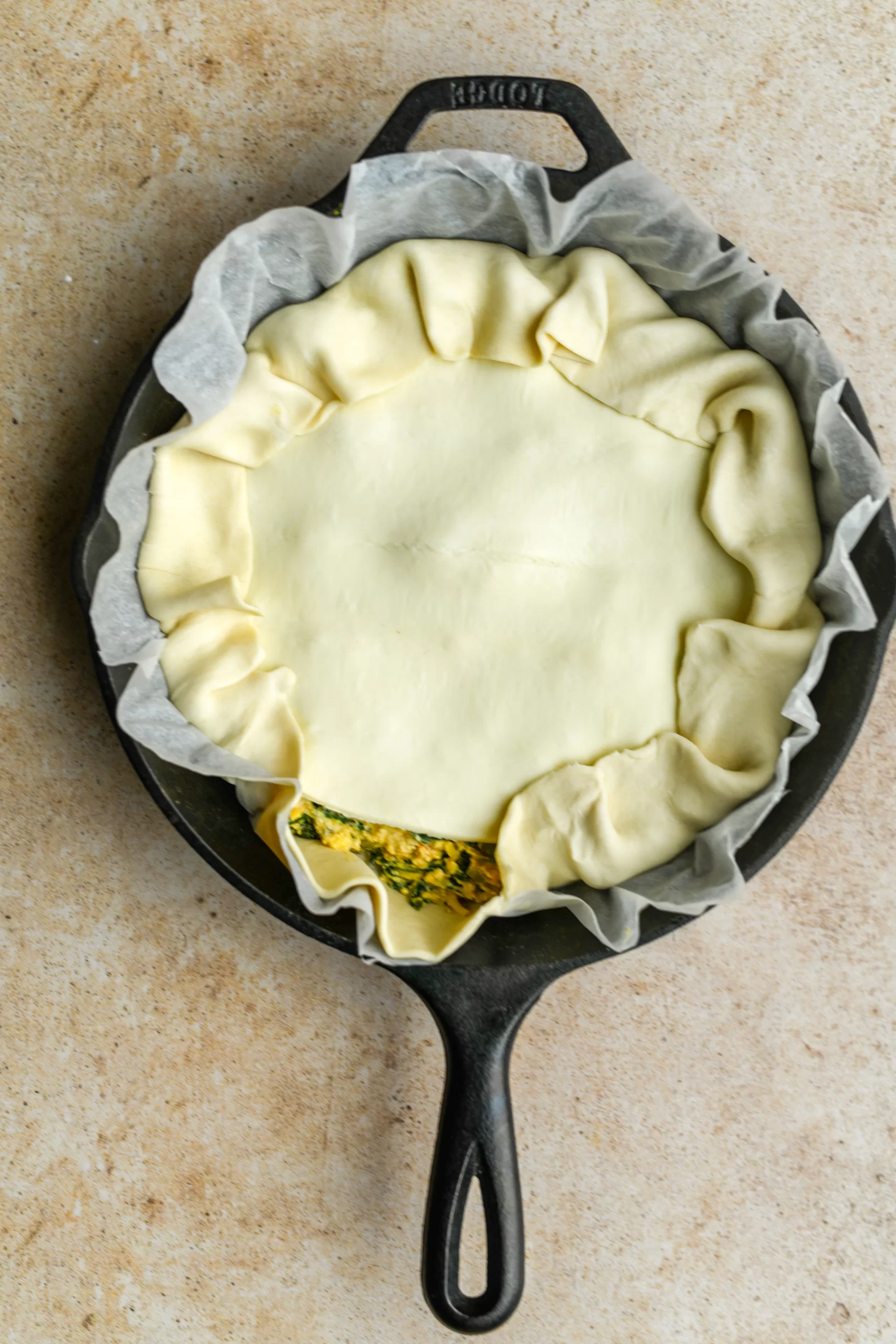 spinach pie filling added to pan topped with puff pastry
